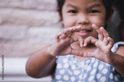 Fototapet Asian little girl making heart shape with hands in vintage color tone