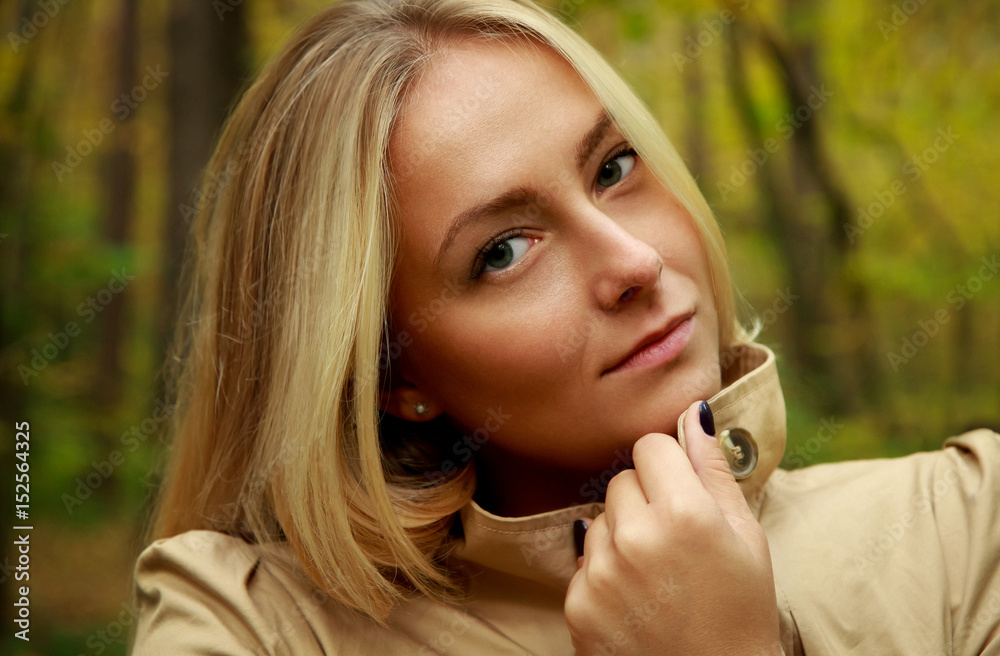 Beautiful blond woman portrait in the forest with green and yellow trees background, wearing beige jacket, fashion beauty model photosession, russian beautiful girl Beautiful blond woman portrait in the forest with green and yellow trees background, wearing beige jacket, fashion beauty model photosession, russian beautiful girl