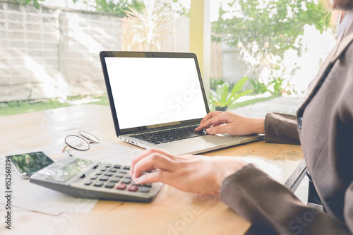 Closeup Business woman using laptop computer with calculator on