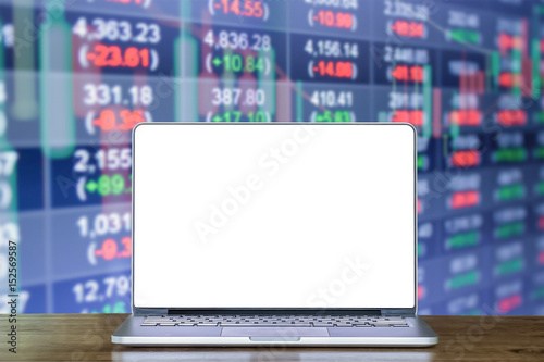 Laptop computer on wood desk with background Double exposure of stocks market chart and stock data in blue on LED display concept. 