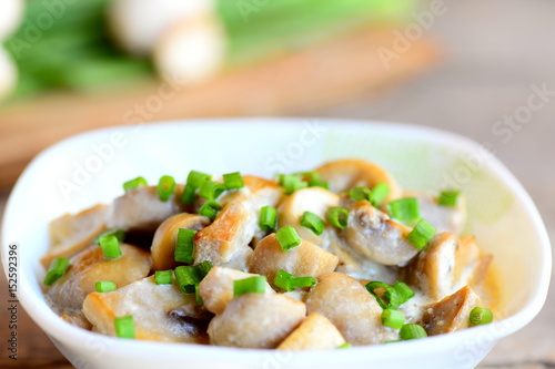Fried mushrooms with sour cream and green onions in a bowl. Vegetarian dish. Simple healthy mushrooms recipe. Closeup