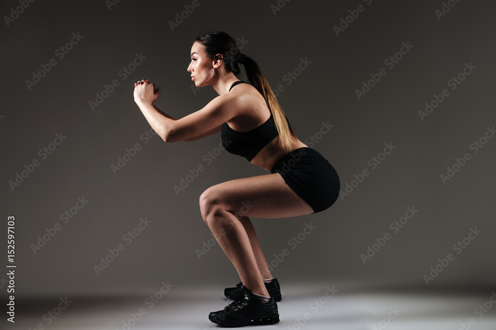 Strong sportswoman make sports exercises over grey background Strong sportswoman make sports exercises over grey background