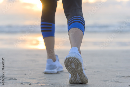 Woman running on the beach at sunrise closeup on shoe. Patong beach, Phuket, Thailand