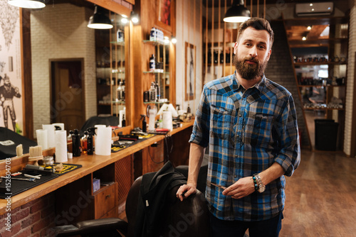 Handsome nice barber standing near his workplace