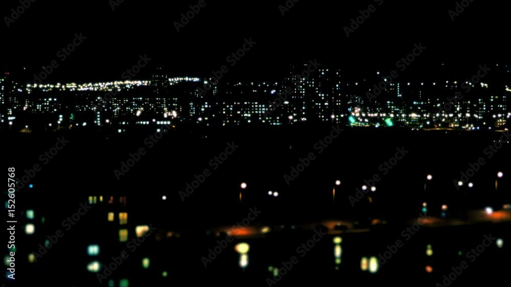 Night City Lights / Big City Landscape / Night Life. City lights twinkle, windows of high-rise buildings light up and go out, cars with headlights drive on roads. Lens blur. Night City Lights / Big City Landscape / Night Life. City lights twinkle, windows of high-rise buildings light up and go out, cars with headlights drive on roads. Lens blur.