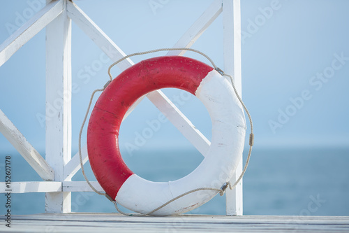 Red and white life bouy floater on wooden bridge on a sea side