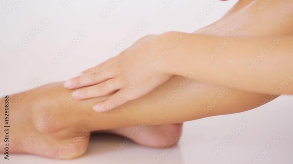woman applying moisturizing cream to her leg woman applying moisturizing cream to her leg