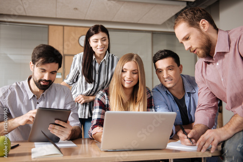 Positive delighted colleagues looking at screen of laptop