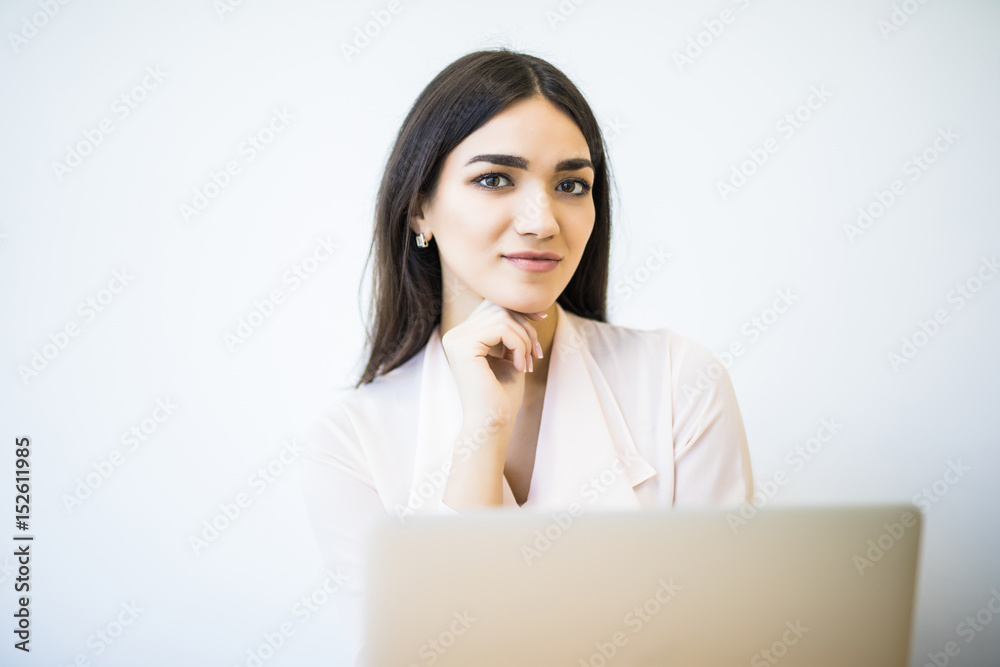 Portrait of a cheerful businesswoman sitting at the table in office and looking at camera Portrait of a cheerful businesswoman sitting at the table in office and looking at camera