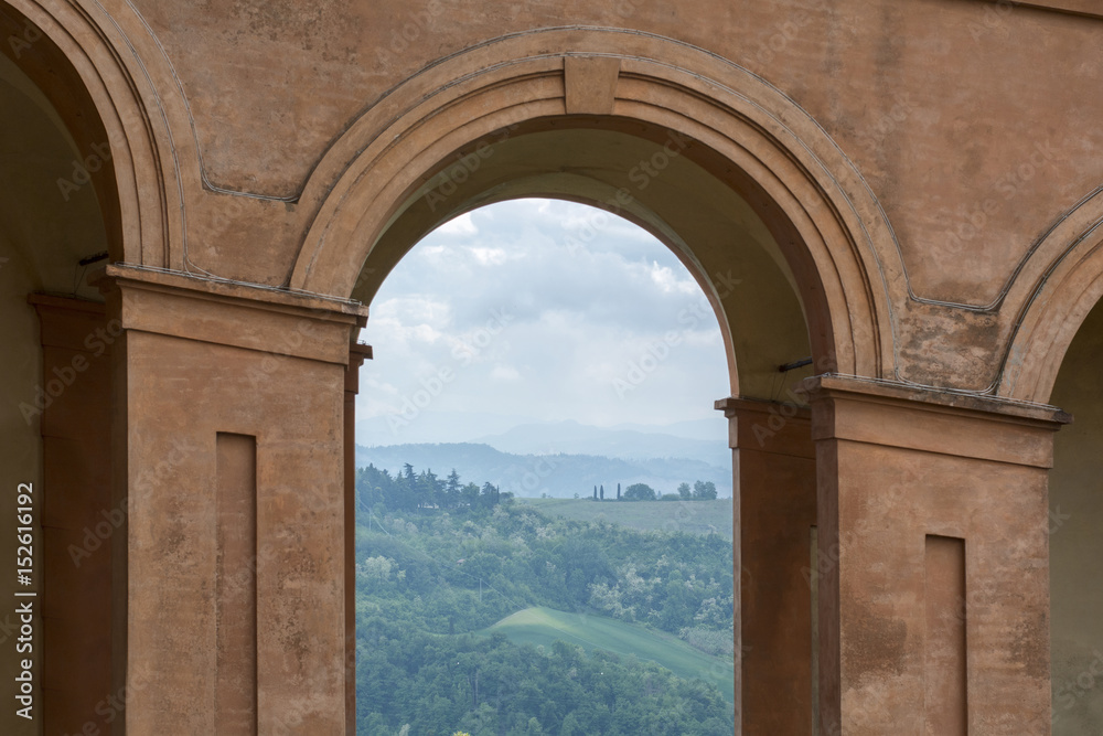 Green fields and cloudy sky in Italy, Bologna through one orange archway
