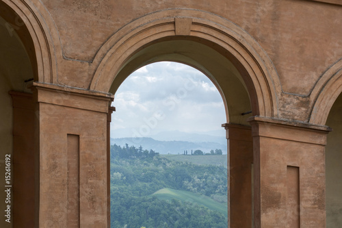 Green fields and cloudy sky in Italy  Bologna through one orange archway