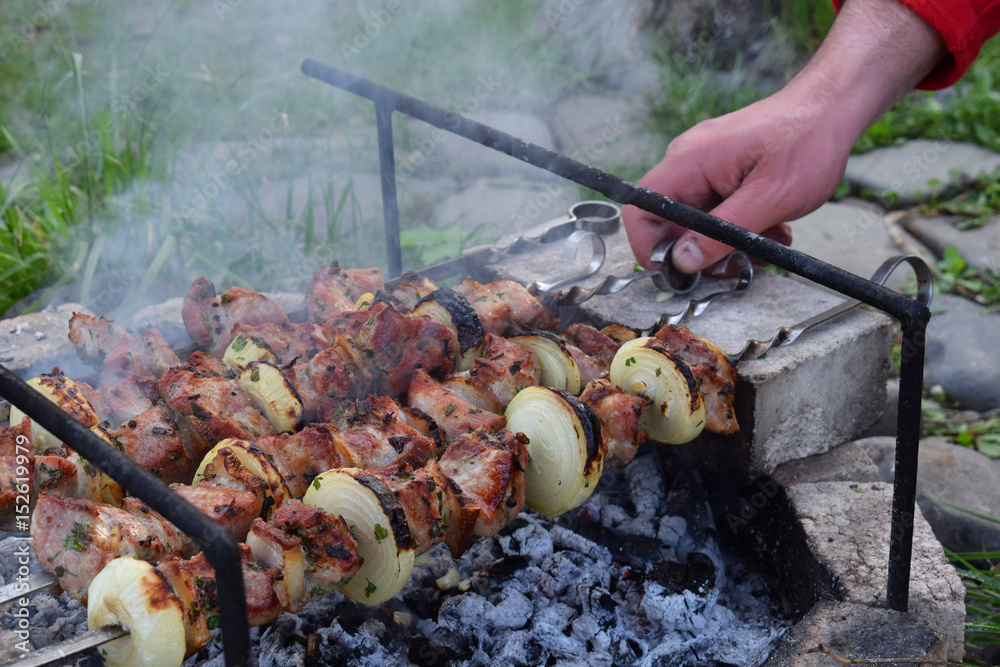 barbecue marinated meat with onion and bacon. Shashlik or Shish kebab  preparing on grill over charcoal in nature. Shashlyk skewered meat . BBQ  grilling. Stock Photo | Adobe Stock
