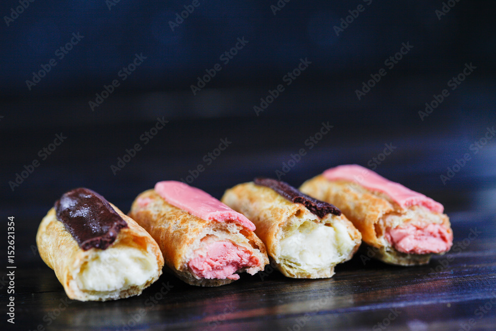 Eclairs on dark wooden background Eclairs on dark wooden background