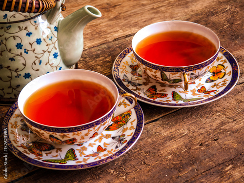 Teapot and glass cups with tea against wooden background