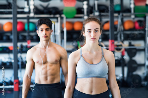 Beautiful young fit couple in modern crossfit gym.