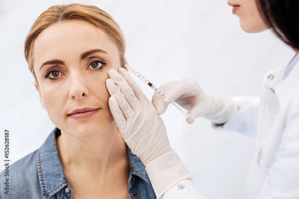 Woman receiving cosmetic injection with syringe Woman receiving cosmetic injection with syringe
