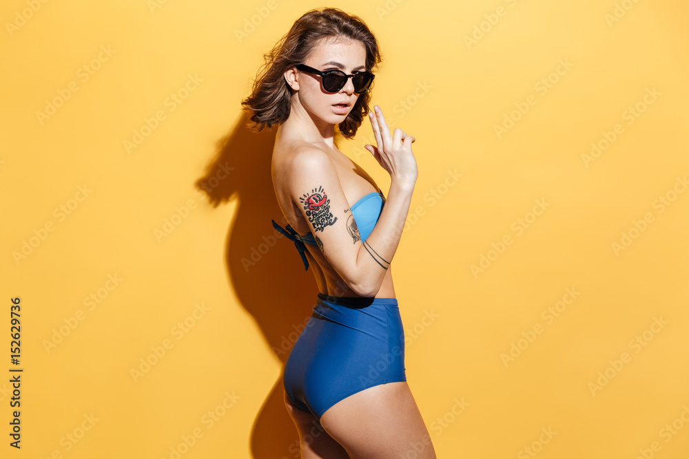 Serious young woman in swimwear showing gun gesture Serious young woman in swimwear showing gun gesture