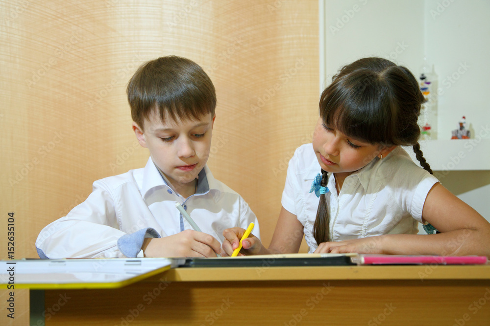 Children draw on paper. Creativity and education concept. The child paints with colored pencils on a white sheet of paper (table)