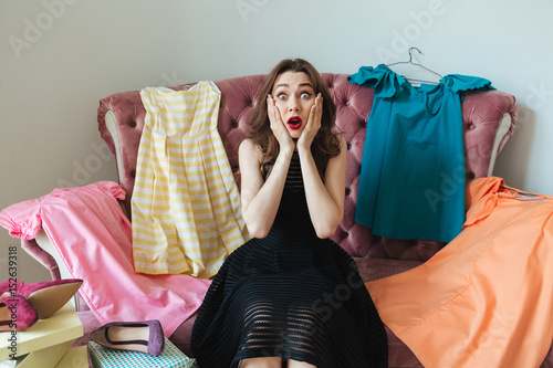 Pretty frustrated woman in dress sitting on a sofa