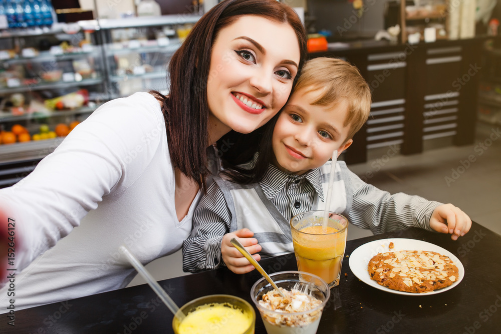A young mother makes selfie with her little son at a table in a cafe A young mother makes selfie with her little son at a table in a cafe