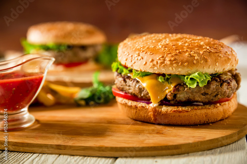 Tasty classic hamburger with beef and tomato sauce on wooden plate. Food concept