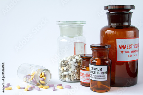 Colorful medical pills in a glass container on a white background.