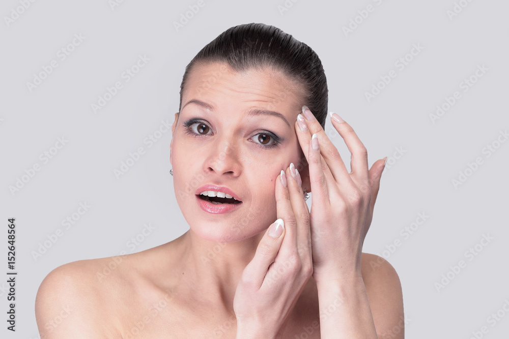 Young woman examining her face and wrinkles that can appear, iso Young woman examining her face and wrinkles that can appear, iso