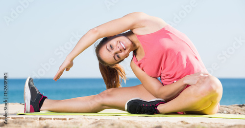 Young sportwoman doing gymnastics at sea beach