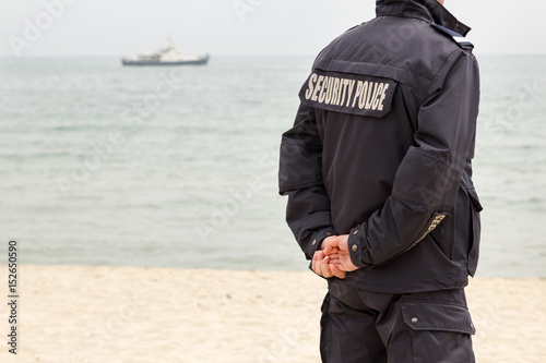 Security police on the seashore with a ship in the distance © Mahlebashieva