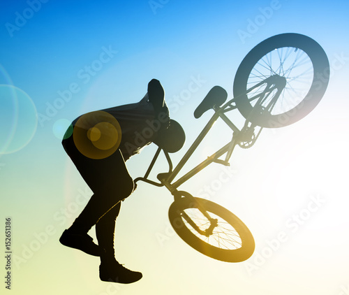 silhouette of bmx rider performing stunts in the air 