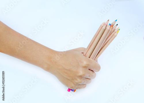 Hand holding colored pencils on white background.