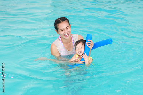 family of mother teaching kid in swimming pool.