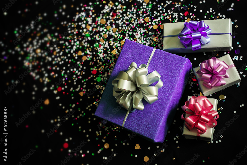 The gift boxes on a black festive background with sparkles The gift boxes on a black festive background with sparkles
