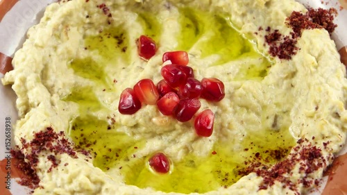 Close-up view of Hummus, decorated with garnet fruit seeds and spices, made from mashed chickpeas dip with tahini, lemon, garlic and olive oil
