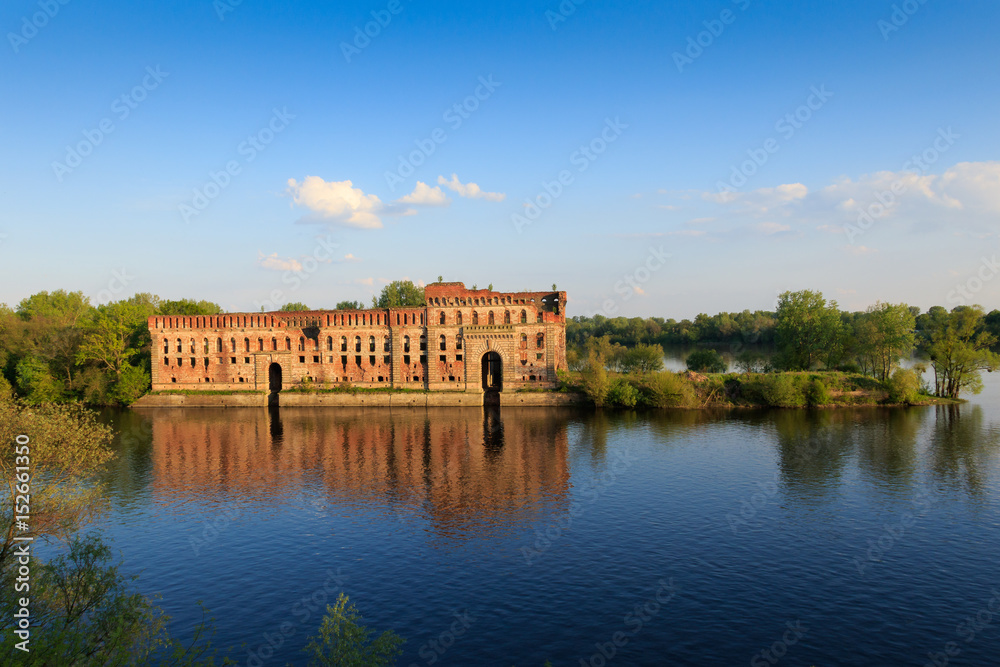 Fototapeta premium Red brick granary at the river with water reflection