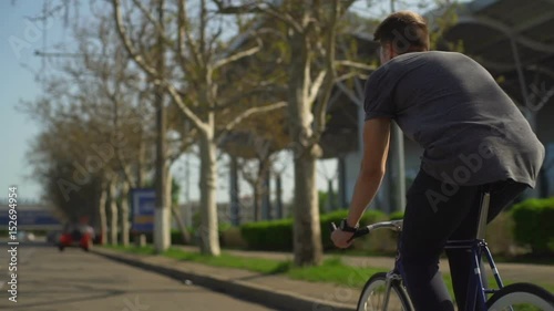 Wallpaper Mural Young man in grey shirt and watches rides his bike on the street slow motion Torontodigital.ca