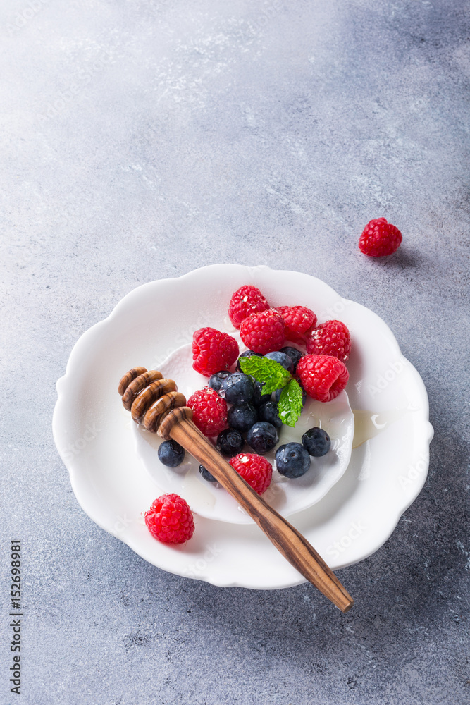 Freshly blueberries and raspberries on white plate with honey. Healthy eating and nutrition concept with copy space. Top view. Freshly blueberries and raspberries on white plate with honey. Healthy eating and nutrition concept with copy space. Top view.