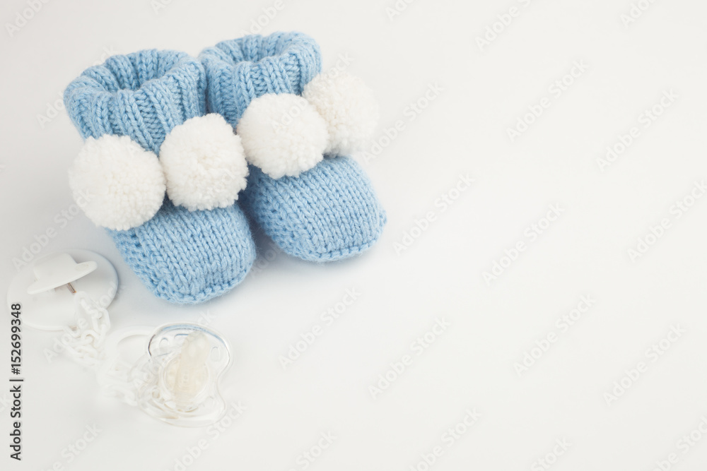 Concept of Infancy and motherhood. knitted newborn baby booties and soother on white background with copy space Concept of Infancy and motherhood. knitted newborn baby booties and soother on white background with copy space