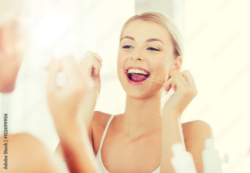 woman with dental floss cleaning teeth at bathroom woman with dental floss cleaning teeth at bathroom