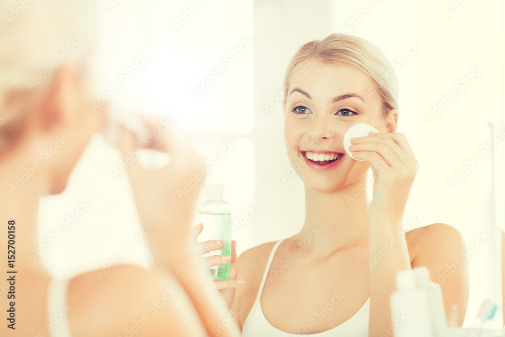 young woman with lotion washing face at bathroom young woman with lotion washing face at bathroom