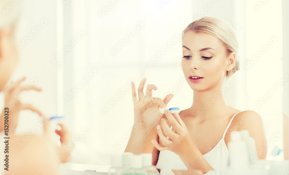 young woman putting on contact lenses at bathroom young woman putting on contact lenses at bathroom