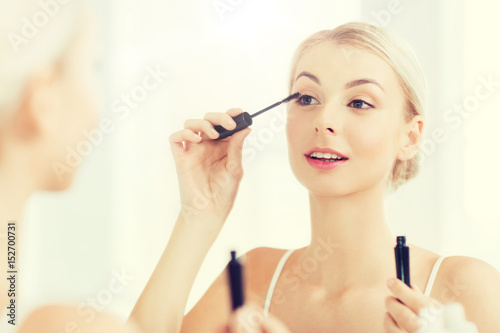 woman with mascara applying make up at bathroom