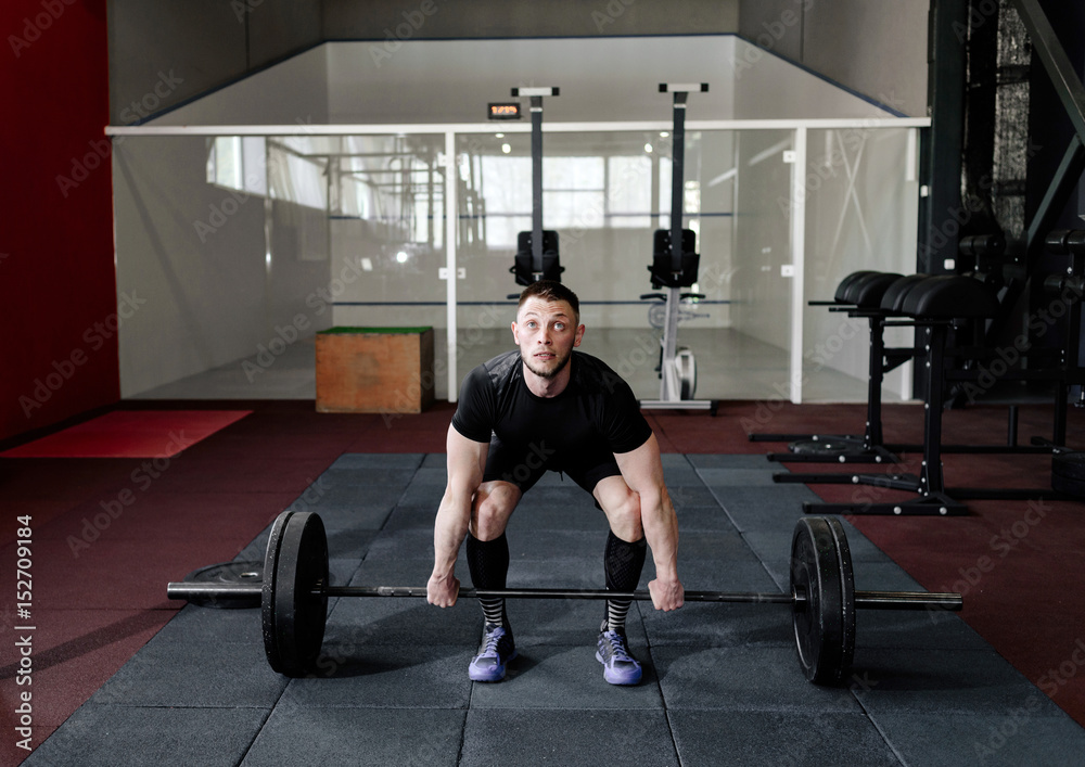 Fit young athlete lifting the barbell in gym. Gym training Fit young athlete lifting the barbell in gym. Gym training