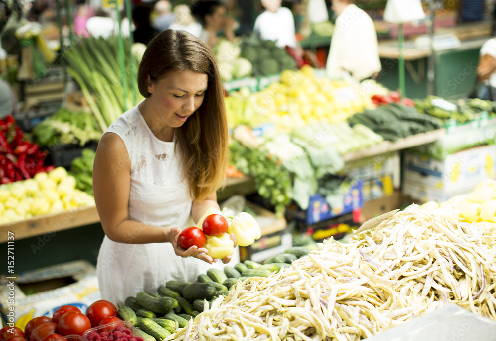 Young woman picking fresh vegetable at the market