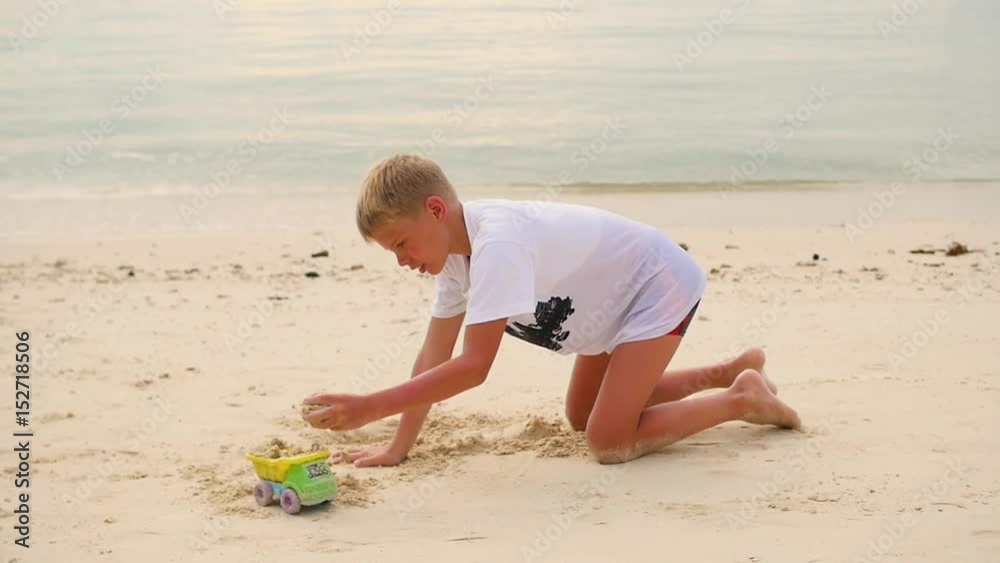 child playing with sand on the beach at sunset time child playing with sand on the beach at sunset time