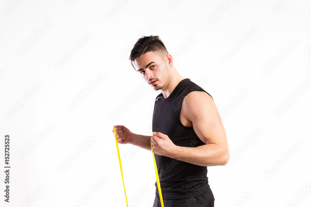 Handsome fitness man working out with rubber band, studio shot.