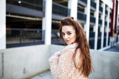 young beautiful happy girl in a coat posing at the street