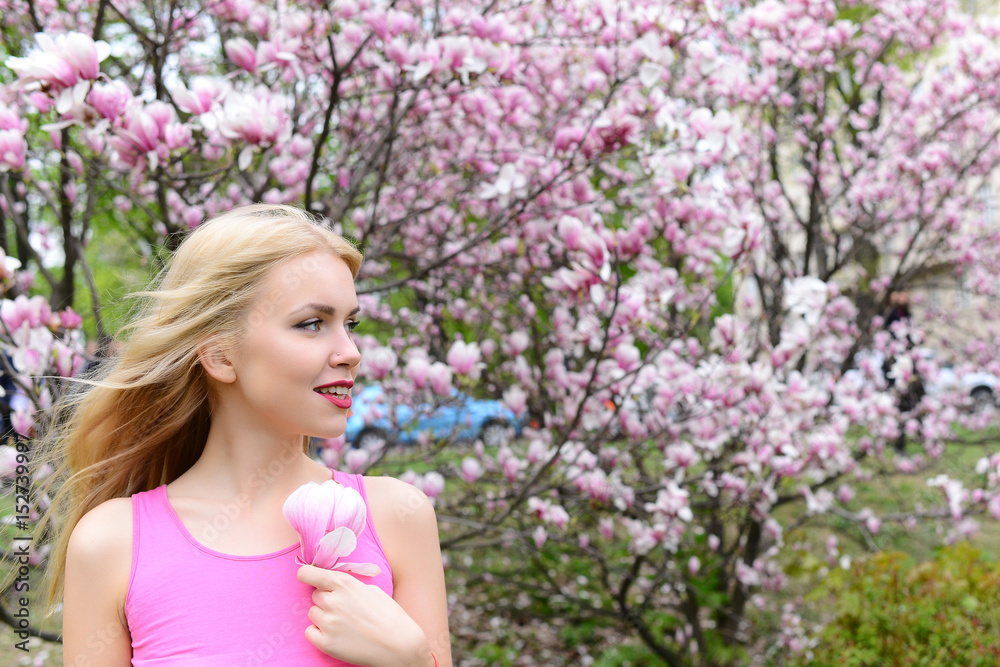 Fototapeta premium young beautiful woman near magnolia tree with flowers
