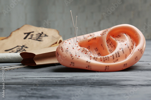 Obraz na plátně Model of ear with acupuncture needles on table