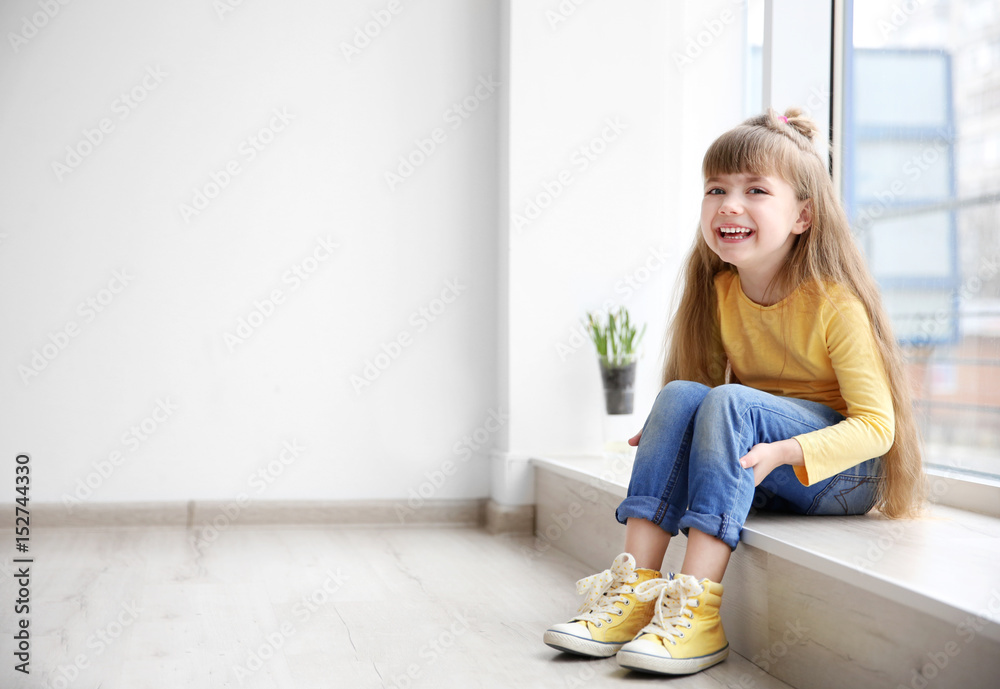 Little fashion girl sitting on window sill in light room - obrazy, fototapety, plakaty 